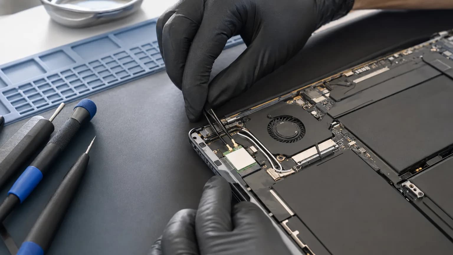 Technician inspecting a laptop Wi-Fi card and its antenna cable connections