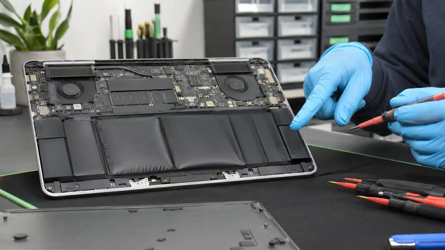 Opened laptop showing an intact swollen battery during careful professional inspection