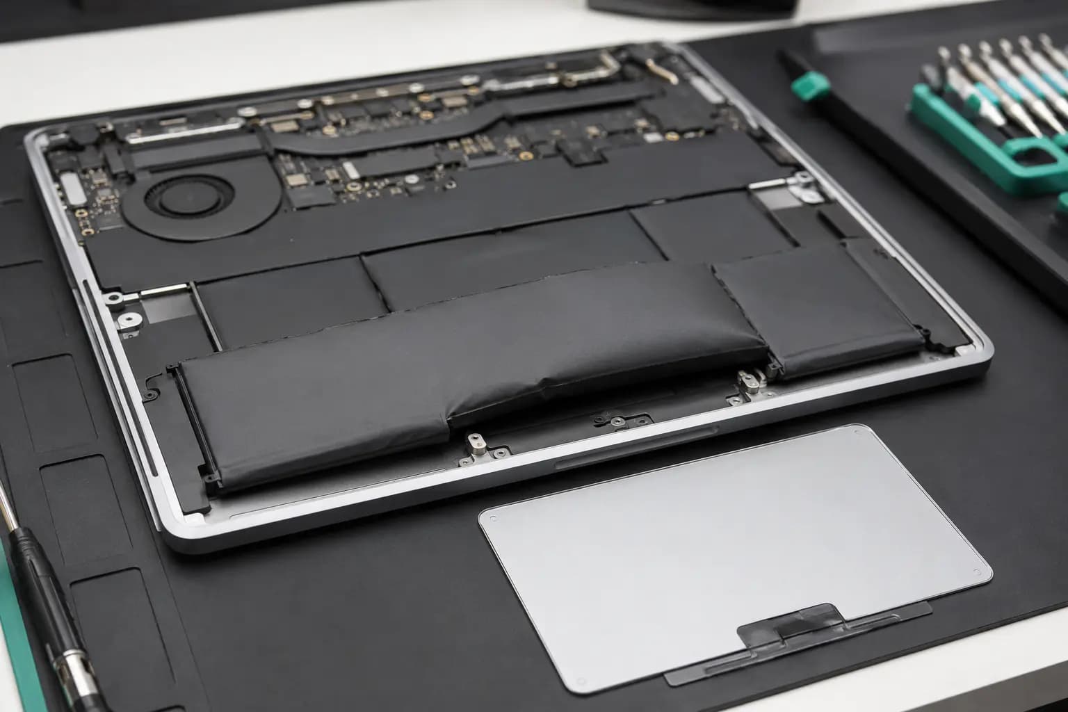 Swollen internal laptop battery lifting from its normally flat position