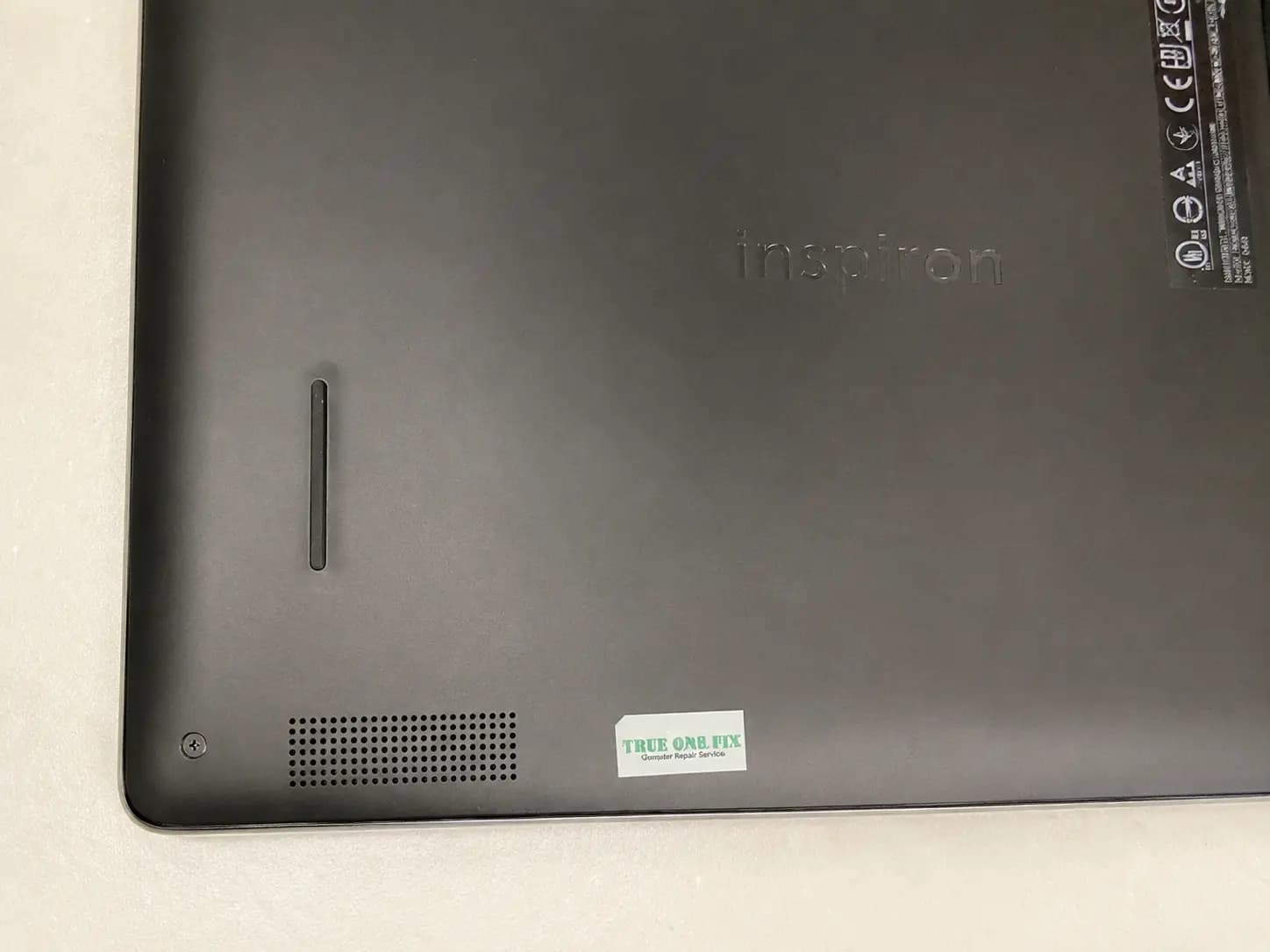 True One Fix tamper-evident warranty label visible on a serviced laptop bottom cover