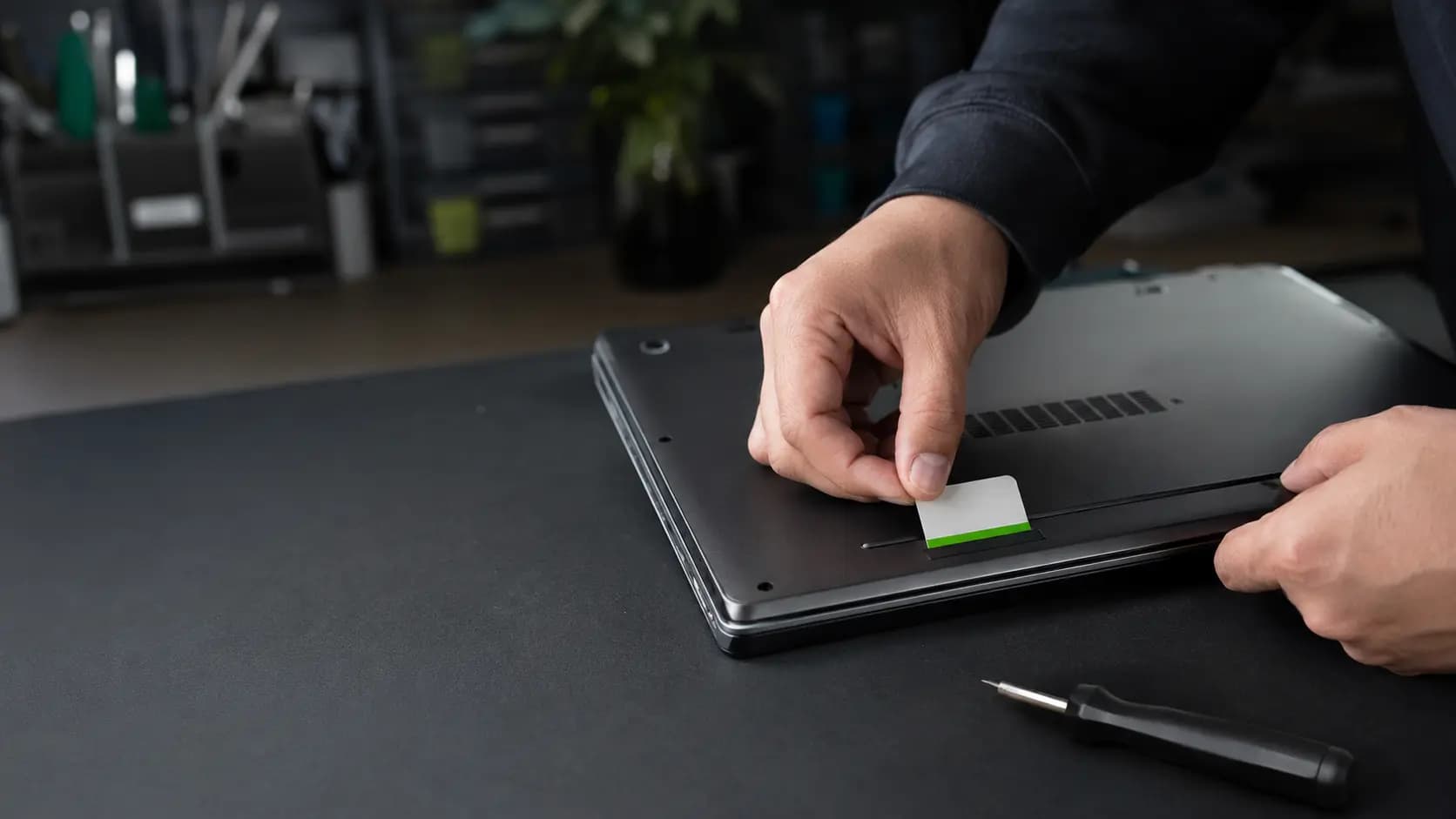 Computer technician applying a tamper-evident service seal to a repaired laptop