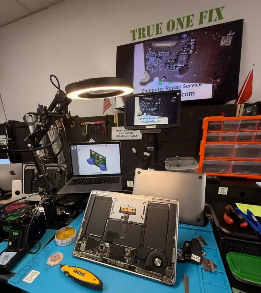 Laptop repair workstation at Trueonefix Tampa with open laptop, micro-soldering tools and diagnostic equipment.